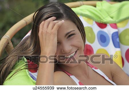 Stock Photo - Portrait of girl (12-13) in bikini relaxing in outdoor chair. Fotosearch