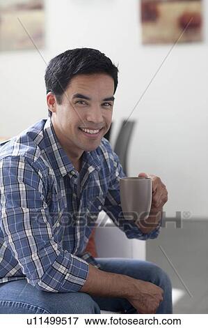Portrait of man drinking coffee in living room View Large Photo Image Stock Photo - Portrait of man drinking coffee in living room. Fotosearch