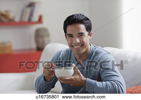 Portrait of man with bowl in living room View Large Photo Image Stock Image - Portrait of man with bowl in living room. Fotosearch