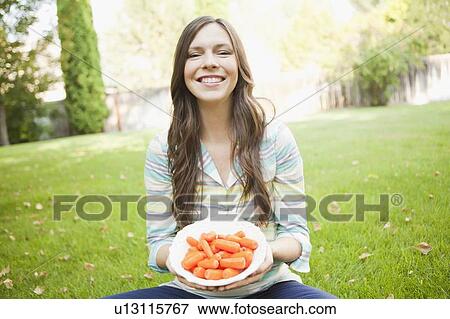 Stock Photo - Portrait of mid adult woman eating carrots. Fotosearch