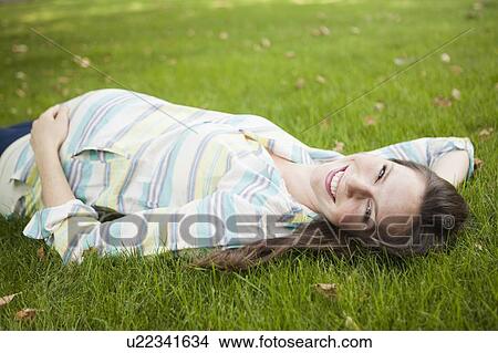 Portrait of pregnant mid adult woman laying down on grass View Large Photo Image Picture - Portrait of pregnant mid adult woman laying down on grass. Fotosearch
