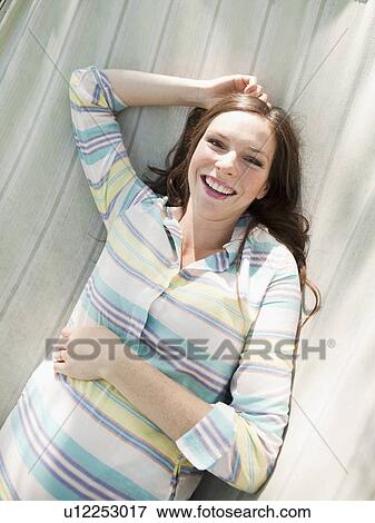 Stock Photo - Portrait of pregnant mid adult woman, directly above. Fotosearch