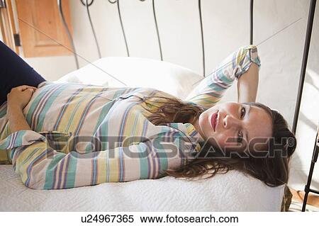 Stock Photography - Portrait of pregnant mid adult woman laying down in bed. Fotosearch