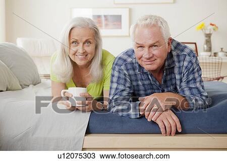 Stock Image - Portrait of senior couple laying on bed. Fotosearch