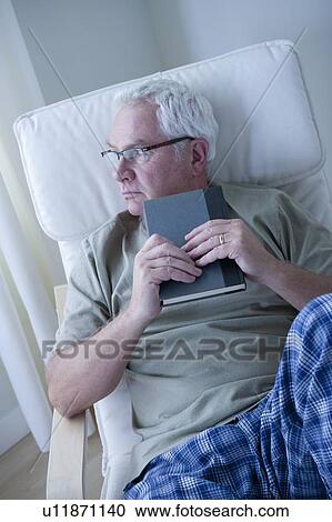 Stock Image - Portrait of senior man holding book. Fotosearch