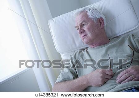 Stock Image - Portrait of senior man holding glasses and thinking. Fotosearch
