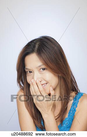 Portrait of smiling woman with hand covering mouth View Large Photo Image Stock Image - Portrait of smiling woman with hand covering mouth. Fotosearch