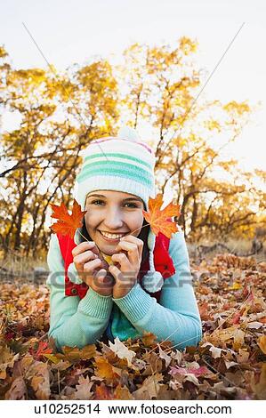 Portrait of smiling young woman lying on autumn leaves View Large Photo Image Picture - Portrait of smiling young woman lying on autumn leaves . Fotosearch