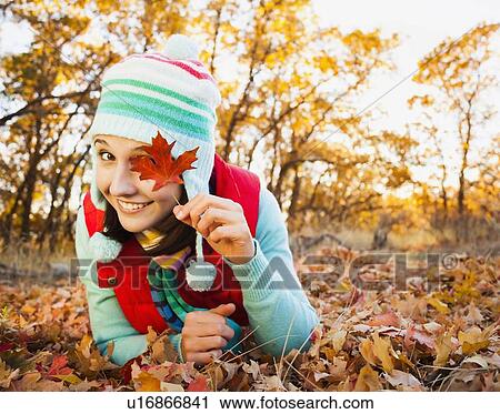 Portrait of smiling young woman lying on autumn leaves View Large Photo Image Stock Image - Portrait of smiling young woman lying on autumn leaves . Fotosearch