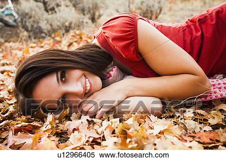Portrait of smiling young woman lying on autumn leaves View Large Photo Image Stock Photography - Portrait of smiling young woman lying on autumn leaves . Fotosearch