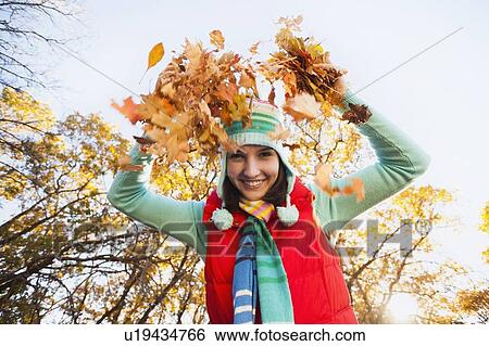 Portrait of smiling young woman throwing dry leaves in autumn forest View Large Photo Image Stock Photograph - Portrait of smiling young woman throwing dry leaves in autumn forest. Fotosearch