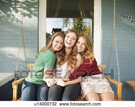 Stock Image - Portrait of three friends on swing. Fotosearch