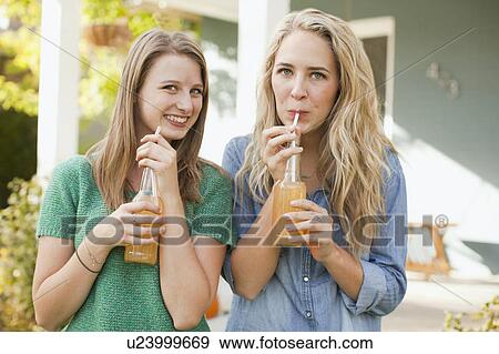 Stock Photo - Portrait of two friends drinking soda through straw. Fotosearch