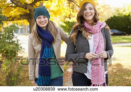 Stock Photo - Portrait of two walking young women wearing hats and scarves. Fotosearch