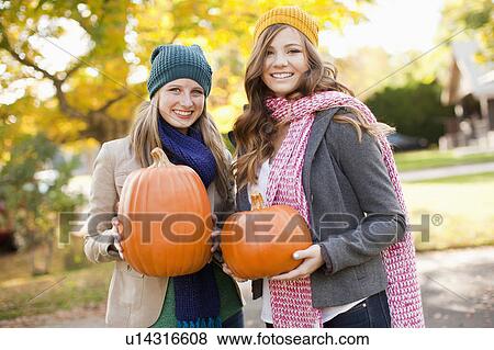Portrait of two young women holding pumpkins View Large Photo Image Stock Photo - Portrait of two young women holding pumpkins. Fotosearch