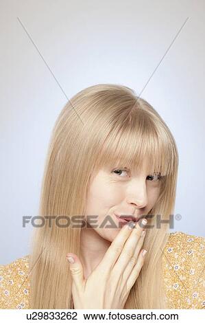 Stock Image - Portrait of woman covering her mouth with hand. Fotosearch