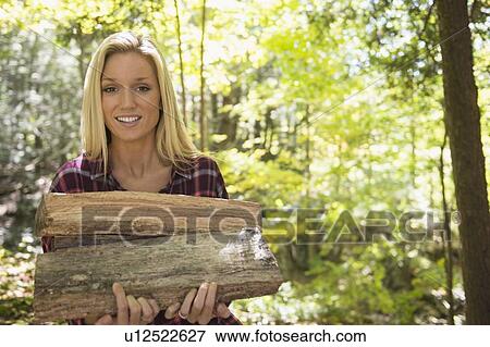 Portrait of woman holding logs in forest View Large Photo Image Stock Photo - Portrait of woman holding logs in forest. Fotosearch