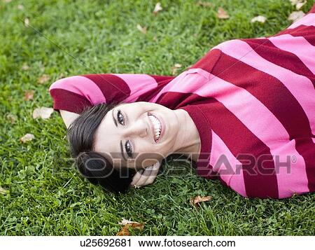Portrait of woman lying on grass View Large Photo Image Stock Image - Portrait of woman lying on grass. Fotosearch