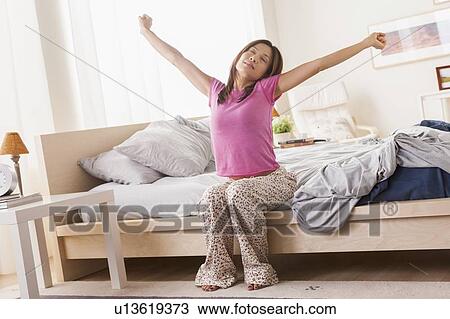 Portrait of woman sitting on bed and stretching her arms View Large Photo Image Stock Image - Portrait of woman sitting on bed and stretching her arms. Fotosearch