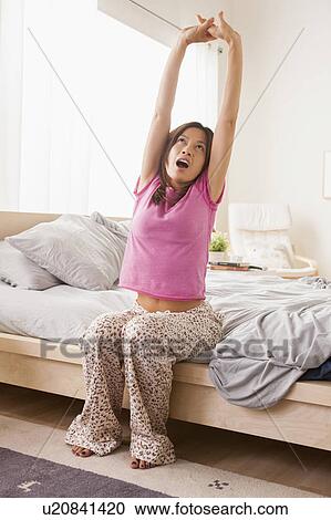 Portrait of woman sitting on bed, stretching her arms and yawning View Large Photo Image Stock Image - Portrait of woman sitting on bed, stretching her arms and yawning. Fotosearch