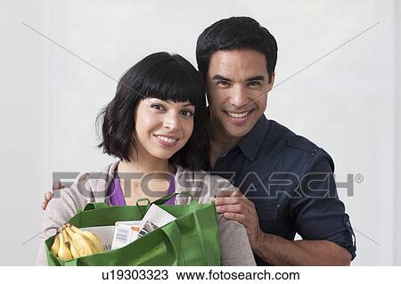Stock Image - Portrait of young couple with shopping bag. Fotosearch