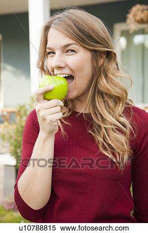 Portrait of young woman biting green apple View Large Photo Image Stock Photography - Portrait of young woman biting green apple. Fotosearch