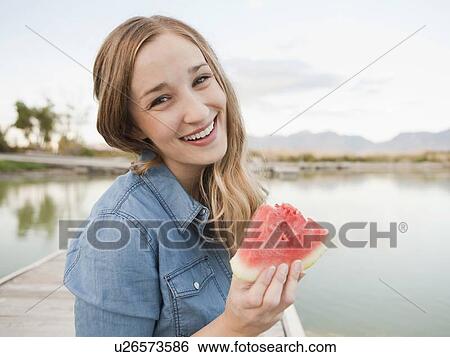 Stock Photograph - Portrait of young woman eating watermelon. Fotosearch