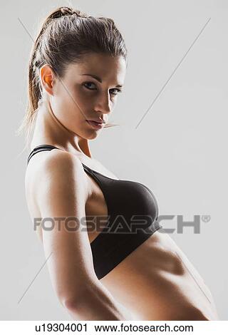 Stock Image - Portrait of young woman exercising, studio shot. Fotosearch