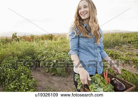 Stock Photo - Portrait of young woman harvesting vegetables. Fotosearch