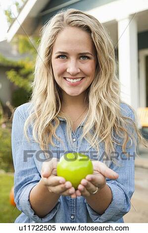 Portrait of young woman holding green apple View Large Photo Image Stock Photography - Portrait of young woman holding green apple. Fotosearch