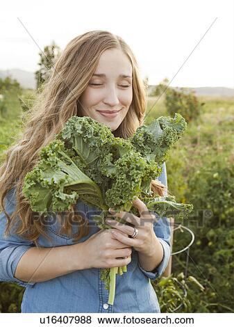 Portrait of young woman holding kale View Large Photo Image Stock Photo - Portrait of young woman holding kale. Fotosearch