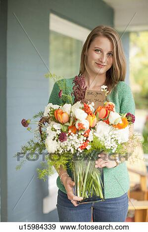 Portrait of young woman holding vase with flowers View Large Photo Image Stock Photo - Portrait of young woman holding vase with flowers. Fotosearch