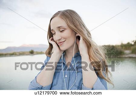 Portrait of young woman listening to mp3 player View Large Photo Image Stock Image - Portrait of young woman listening to mp3 player. Fotosearch