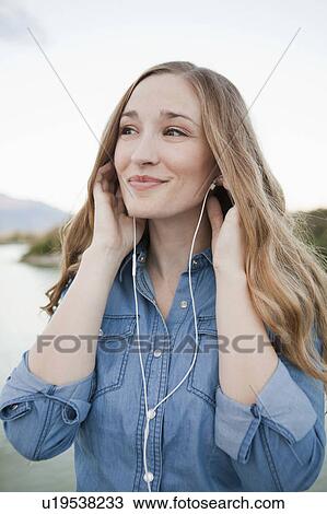 Portrait of young woman listening to mp3 player View Large Photo Image Stock Image - Portrait of young woman listening to mp3 player. Fotosearch