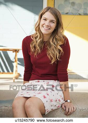 Stock Image - Portrait of young woman sitting on porch. Fotosearch
