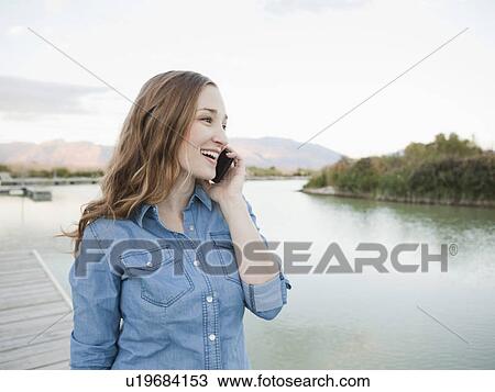 Stock Image - Portrait of young woman talking on phone. Fotosearch