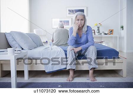 Stock Image - Senior couple after quarrel sitting on bed. Fotosearch