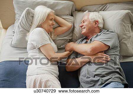 Senior couple laying on bed and laughing View Large Photo Image Stock Photo - Senior couple laying on bed and laughing. Fotosearch
