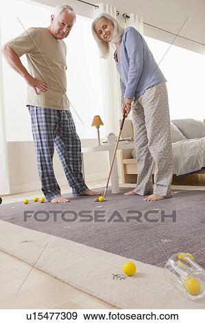 Stock Photo - Senior couple playing mini golf at home. Fotosearch