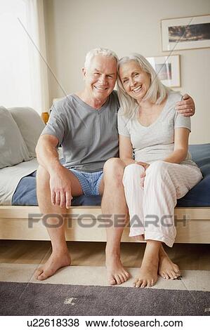 Senior couple sitting on bed in close embrace View Large Photo Image Stock Photo - Senior couple sitting on bed in close embrace. Fotosearch