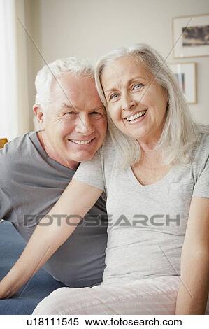 Stock Photography - Senior couple sitting on bed in close embrace. Fotosearch
