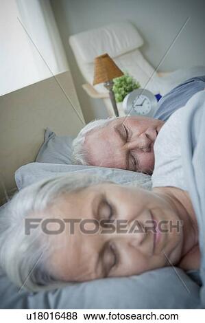 Stock Photo - Senior couple sleeping in bed. Fotosearch