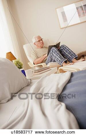 Senior man sitting in bedroom and reading book View Large Photo Image Stock Photo - Senior man sitting in bedroom and reading book. Fotosearch