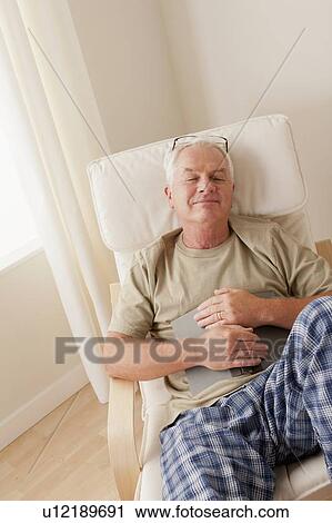 Stock Image - Senior man taking nap and holding book. Fotosearch