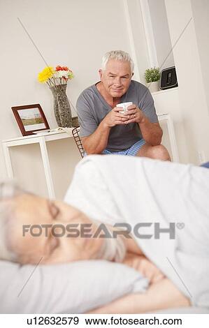 Senior man with coffee cup looking at sleeping wife View Large Photo Image Stock Photo - Senior man with coffee cup looking at sleeping wife. Fotosearch