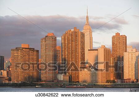Stock Image - Skyline with Empire State Building at sunset. Fotosearch