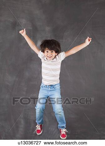Studio portrait of boy (6-7) jumping in front of blackboard View Large Photo Image Stock Photo - Studio portrait of boy (6-7) jumping in front of blackboard. Fotosearch