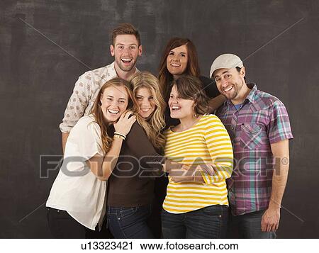 Stock Image - Studio portrait of group of friends embracing. Fotosearch