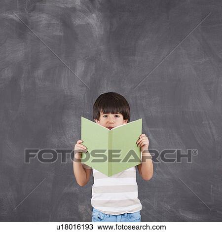 Stock Image - Studio shot of boy (6-7) reading. Fotosearch