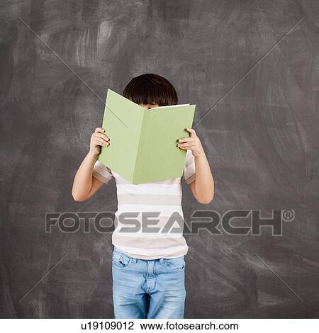 Stock Image - Studio shot of boy (6-7) reading. Fotosearch